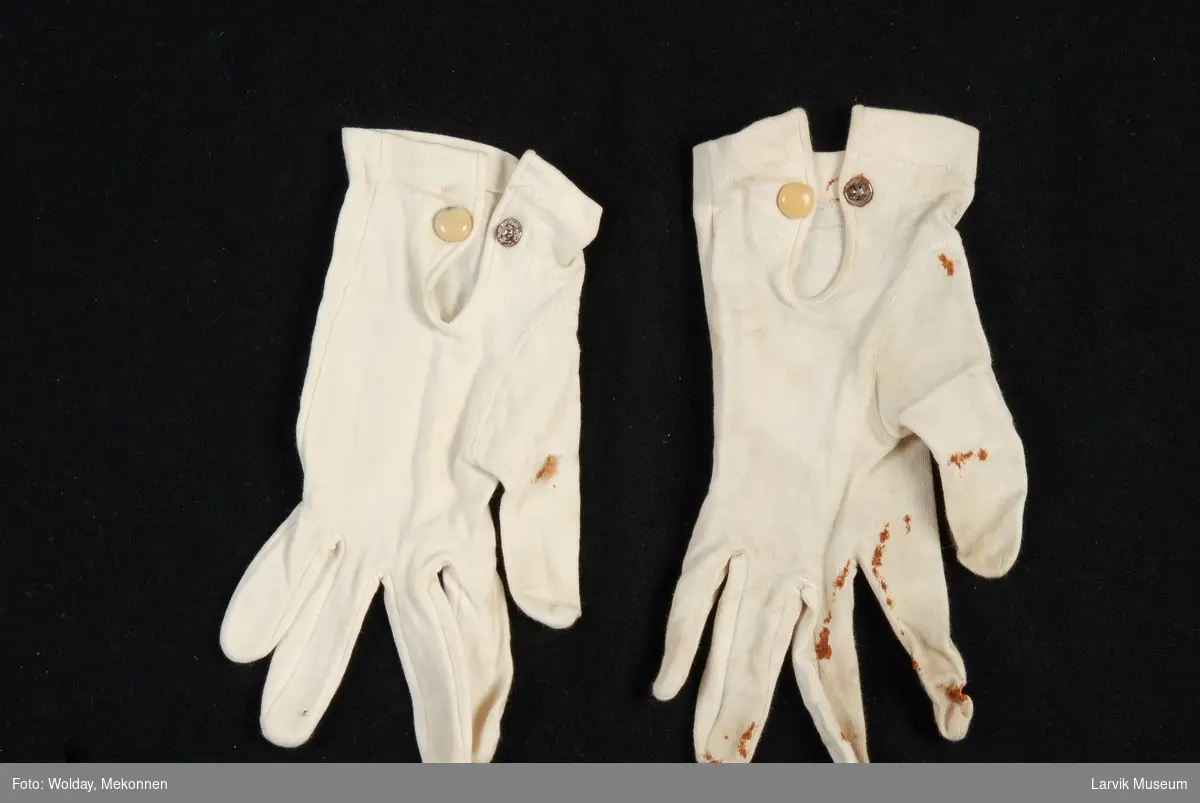 Et par hvite hansker med stikninger og beige trykknapp