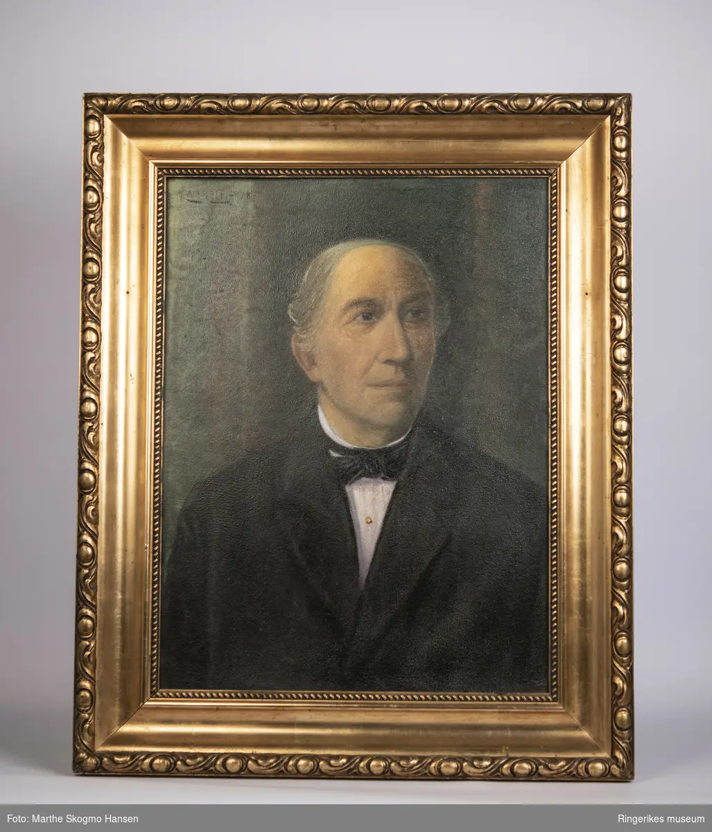 Portrett av eldre Jørgen Moe på grønn bakgrunn med svart jakke med slag, hvit skjorte og svart halssløyfe.