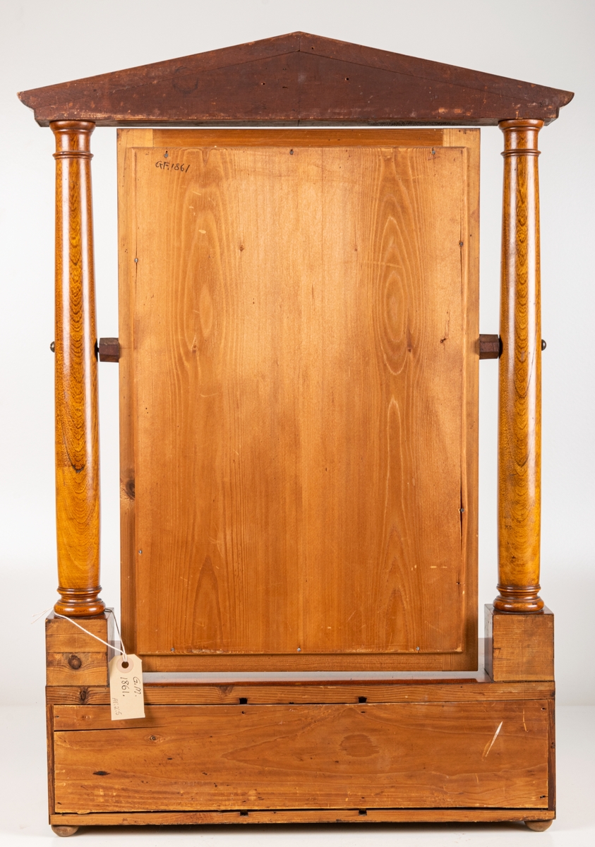 Toilettspegel, Karl-Johanstil, 1800-talet början. Av mahogny, med lådor. Spegeln rörlig mellan två pelare med överstycke. Spegellåda innehållande en större mittlåda och 4 smalare sidolådor.