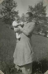 En eldre kvinne holder et lite barn. Tekst i album: 1939.