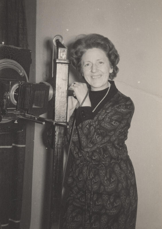 Kvinnelig fotograf poserer med eldre storformat platekamera
