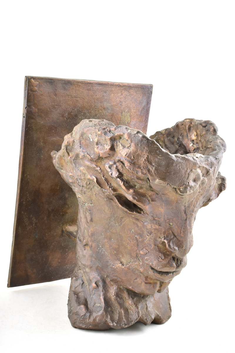 Skulptur i brons av Henrik Allert. Ansikte monterad på bronsskiva för upphängning på vägg.