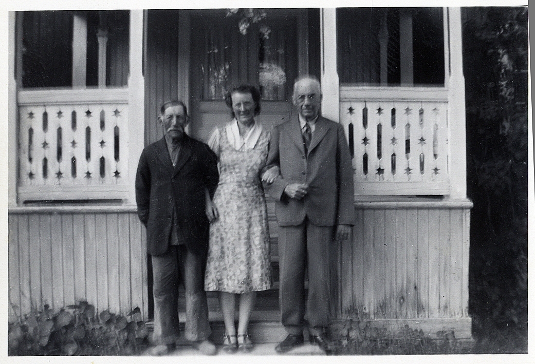 Två äldre män och en ung kvinna arm i arm framför en veranda i Forsa, Hälsingland.