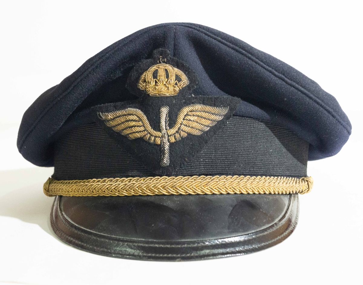 Flygvapnet. Hakrem m/1930 (senare benämd mössträns) och flygemblem m/1951 för reservofficer. (Propellern är i silvertråd, och i övrigt är märket i guldtråd.)