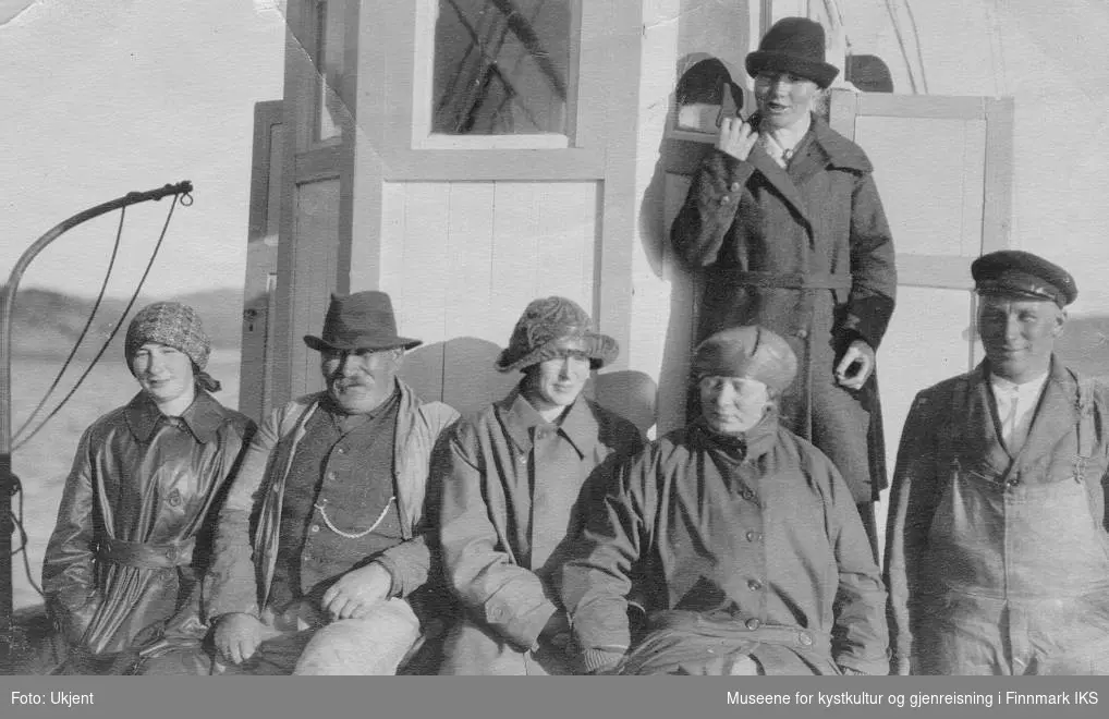 Seks voksne foran styrhuset om bord på båten Ruth. Andre person fra venstre er Johan Normann Pedersen. Mannen lengst til høyre er hans sønn Ragnvald Nicolai Normann. De andre fire personer på bildet er kvinner, muligens også medlemmer av familien Normann fra Melkøya i Finnmark. Bildet er tatt på 1930-tallet.