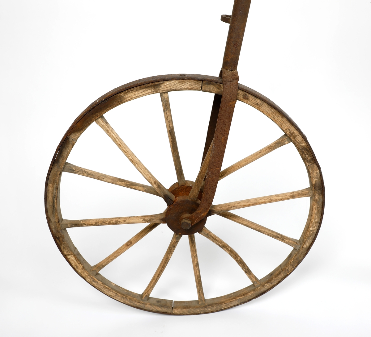 Veltepetter i med hjul av tre og stang av metall. Justerbart sete og pedaler. Sete trukket i lær. Styreholker av tre.