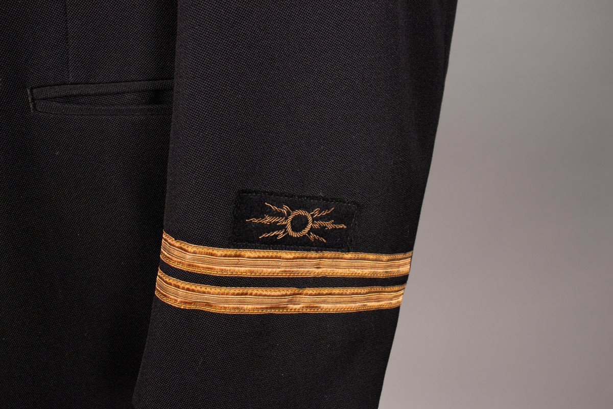Telegrafist uniformjakke med distinksjoner på ermene. To striper.  8 gullfargede knapper. To innerlommer og to stikklommer foran.