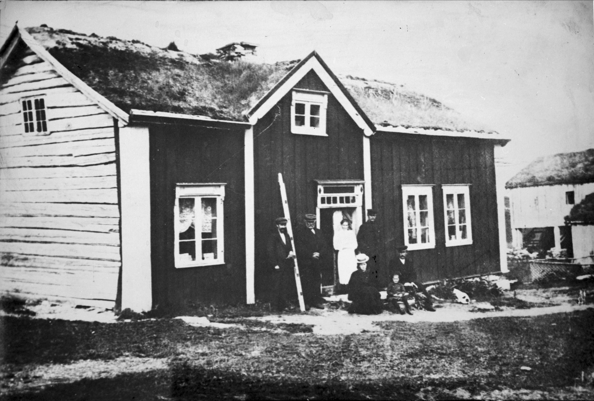Hovedbygningen til Sandtorg bygdetun, fotografert på sin opprinnelige plass i Sørvik. Personer på trappen foran huset.