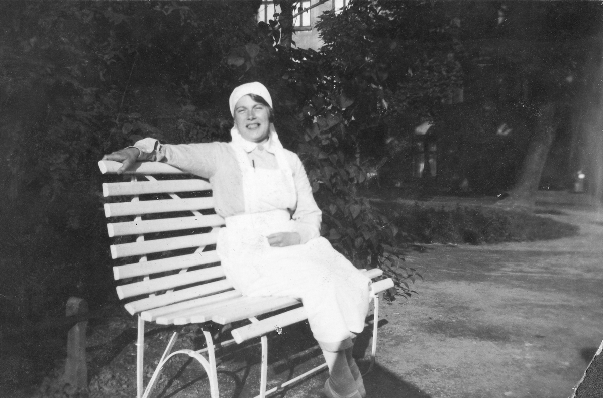 Kvinne i sykepleieruniform på en benk.