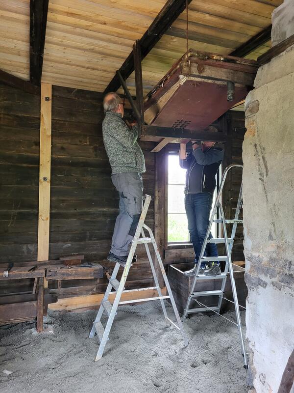Mann på gardintrapp driver med restaureringsarbeid inne i en gammel smie.