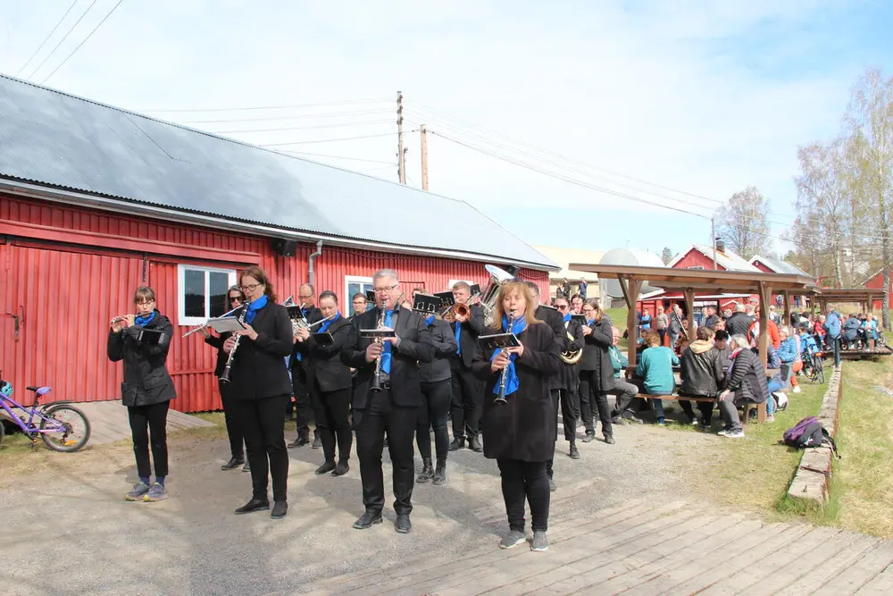 Foto av oppstilte uniformerte mennesker som spiller instrumenter.