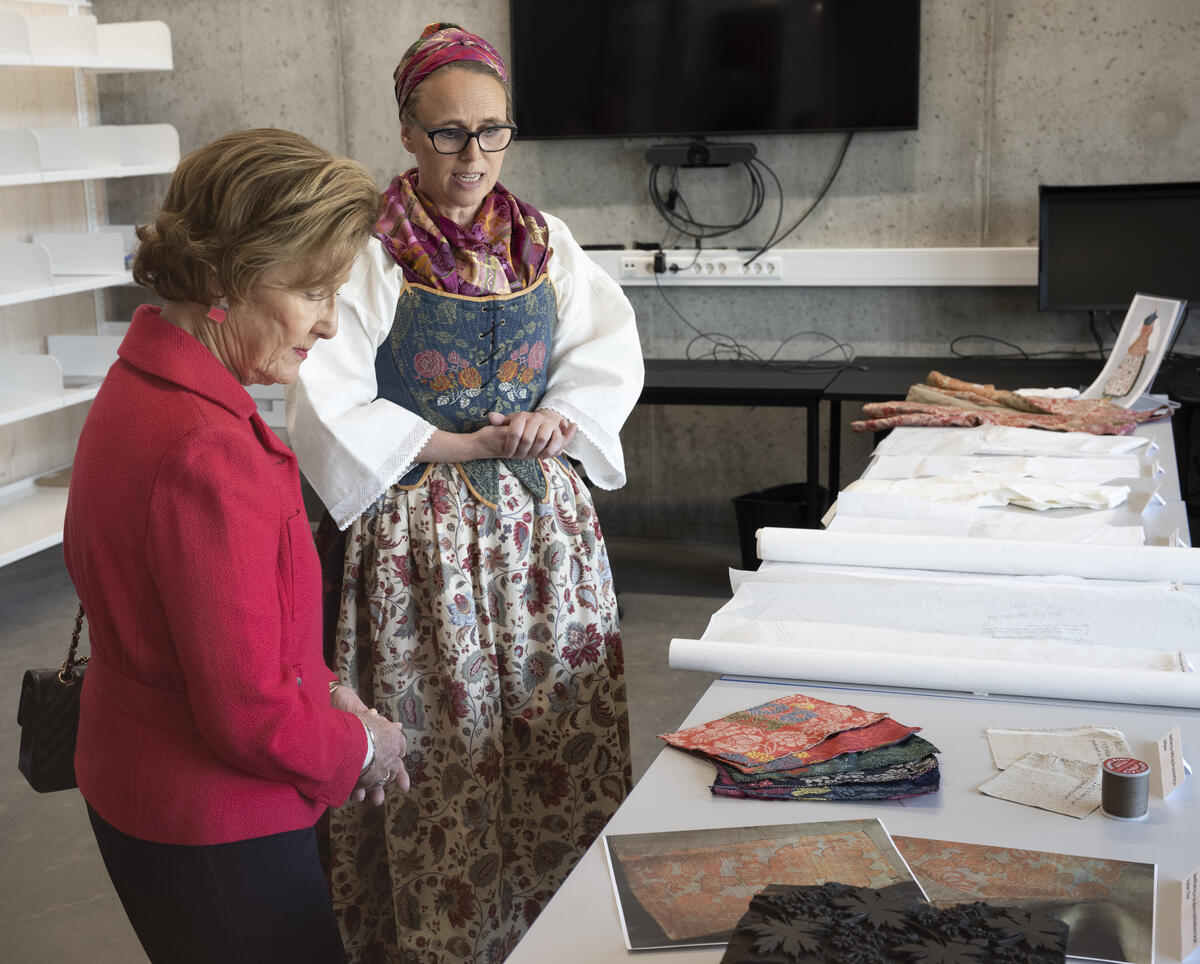 Hennes Majestet Dronning Sonja under omvisning i det nye bevaringssenteret, her i samtale med tekstilregistrator Helga Møller Berg.