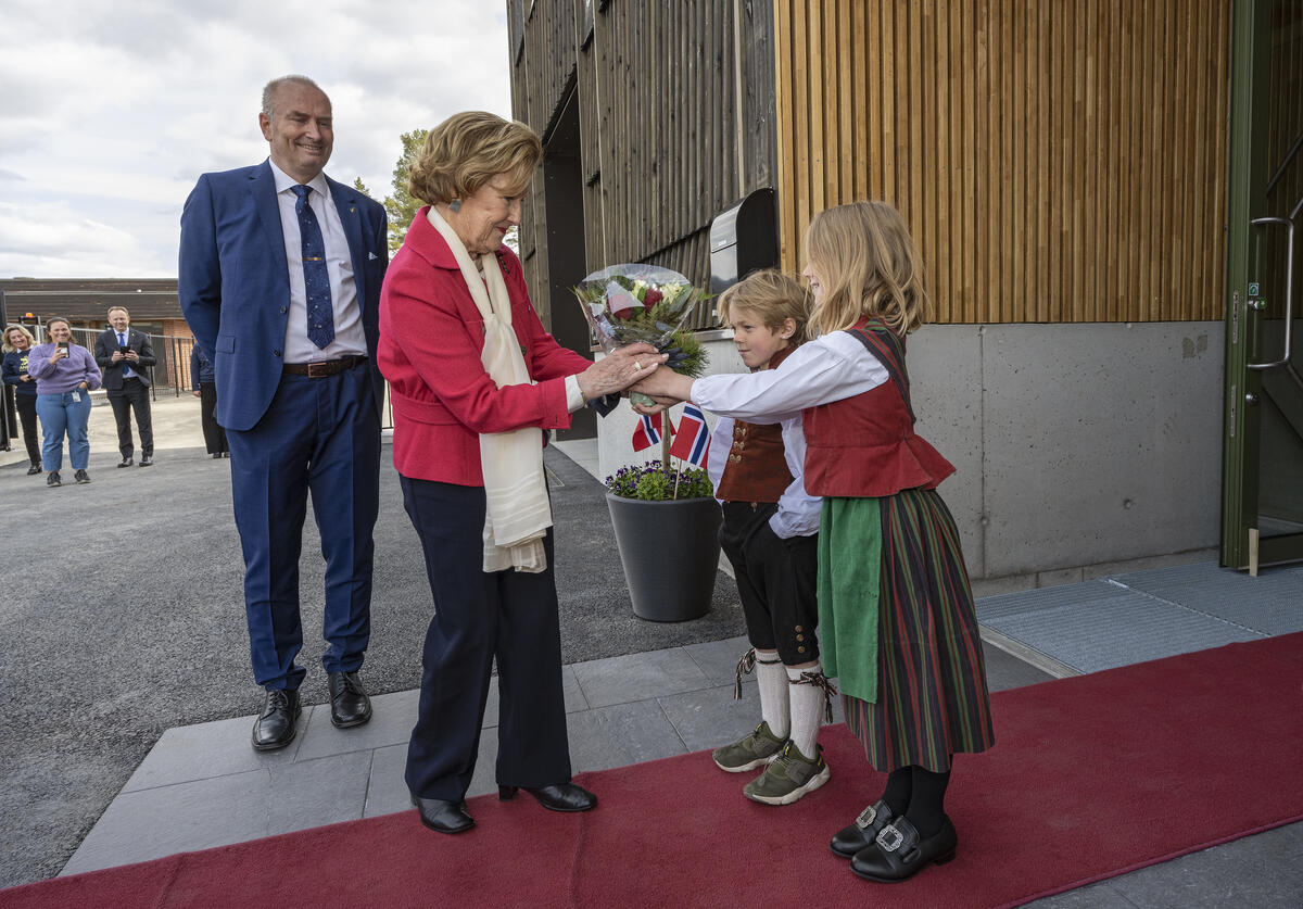 Fra åpningen av Anno bevaringssenter i Elverum, Innlandet 28. april 2022. Hennes Majestet Dronning Sonja ankommer, og Lina (9) og Kåre (7) Bjørnstad overrekker blomster. T.v. administrernede direktør i Anno museum, Sven Inge Sunde.