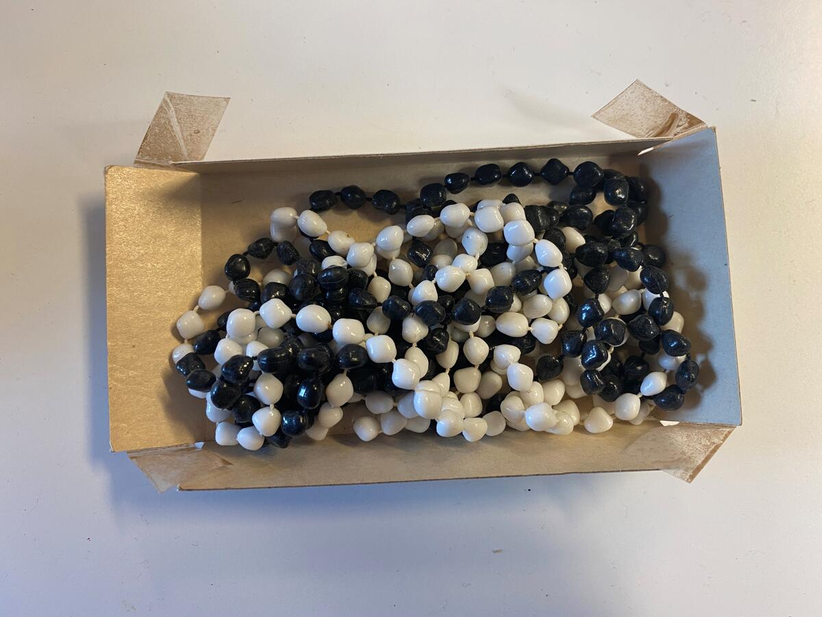 Två stycken halsband, ett med svarta plastpärlor och ett med vita plastpärlor. Vardera 125 cm långt.
Troligtvis från Violet Bergdahls dödsbo.