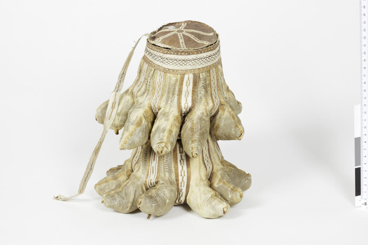 28557. En pose av skinn av måkeføtter med mose til lamper. Høide 24-25 cm. Angmagsalik. 
