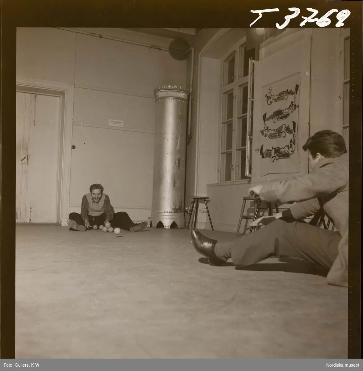 1677 B Konstfackskolan (tösen Boheman). Lek och spel i ateljén. Två manliga elever sitter på golvet och rullar bollar emellan sig.