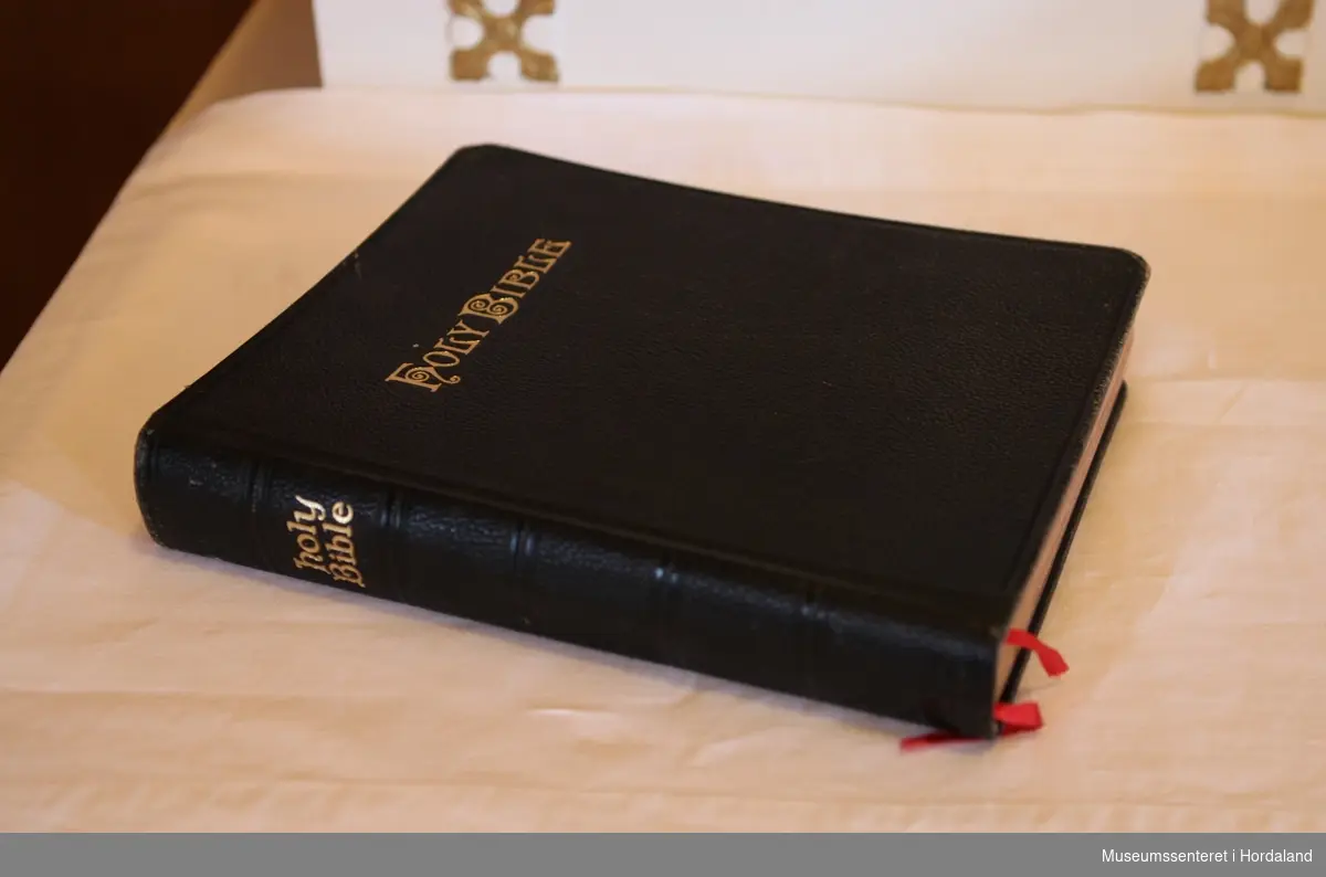 Stor, svart bibel med tittelen "Holy Bible" i gylne, dekorative bokstaver på forside og rygg.