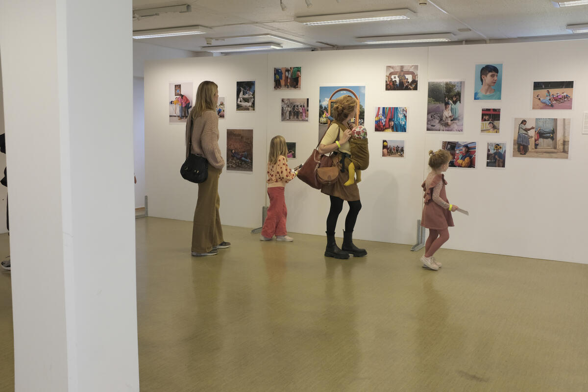 Mennesker ser på bilder på en vegg i en utstilling