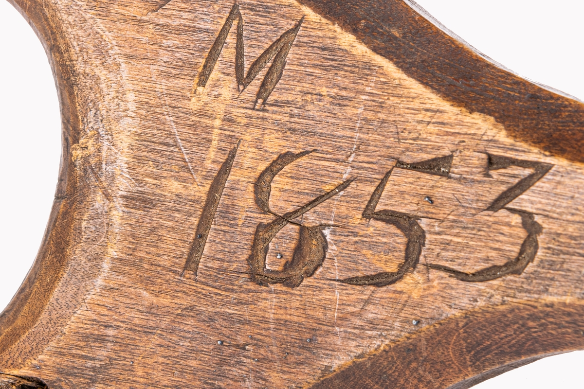 Urgröpningsredskap. Kort, bågböjt liejärn fäst i ändarna på träklyka av ek, klykans grenar linade med rottning. Ristat "M 1853".