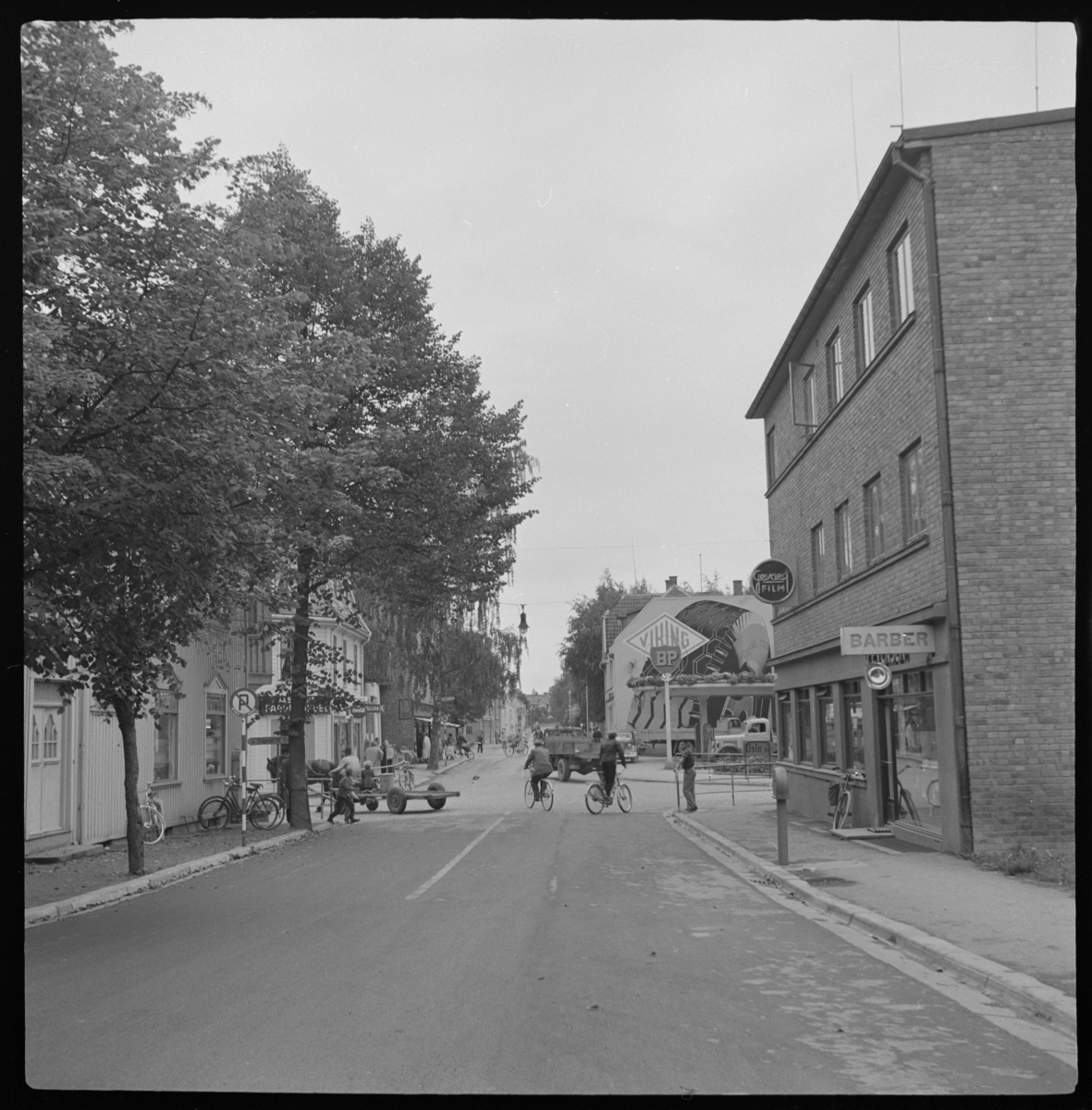 Askim i Indre Østfold kommune, Skolegata med videreføring i Rådhusgata, tidligere Eidsbergveien. Syklister, hestekjøretøy og biler i gata.