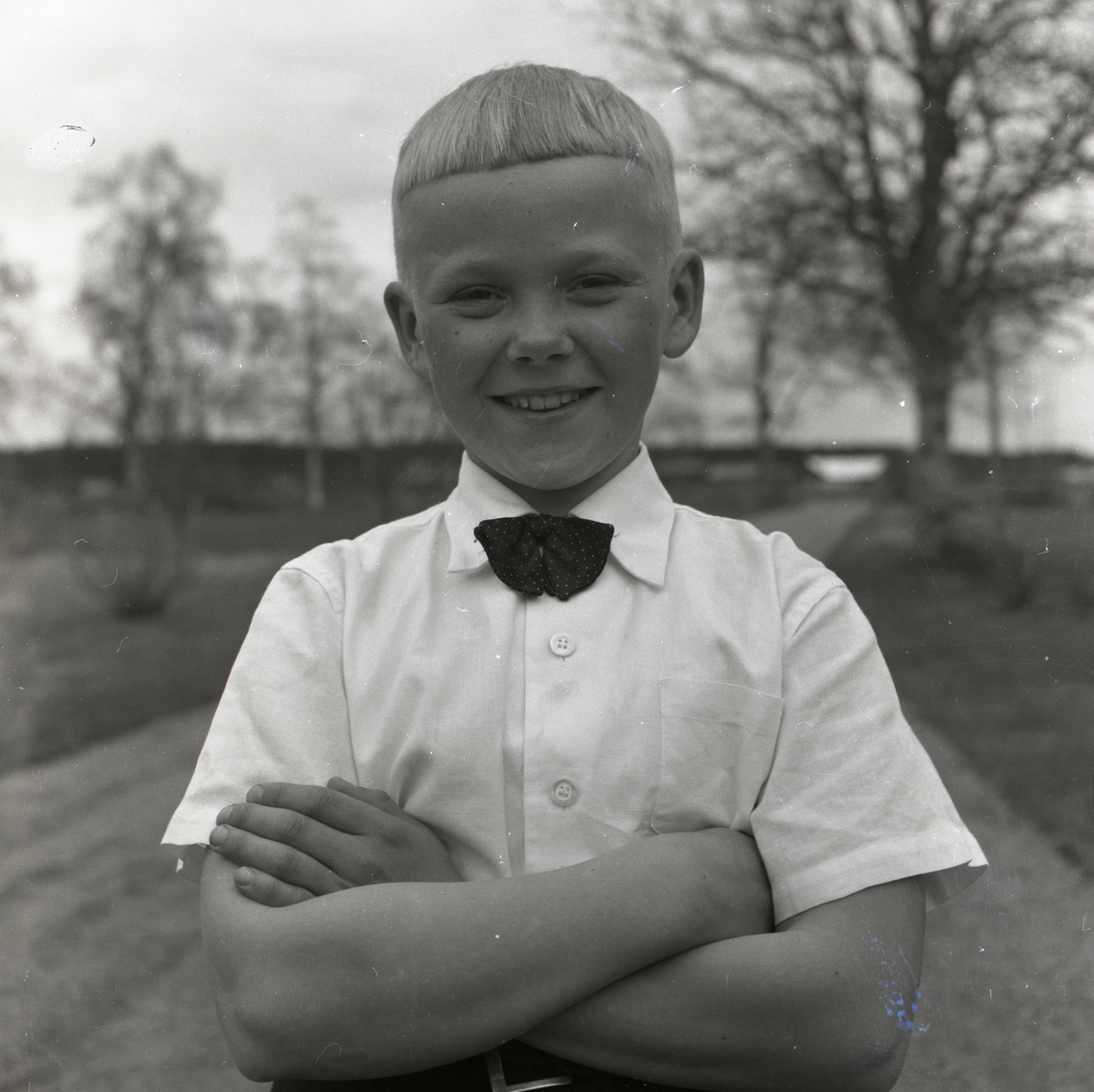 En av Hildings söner med fluga och skjorta poserar leende den 21 maj 1956.