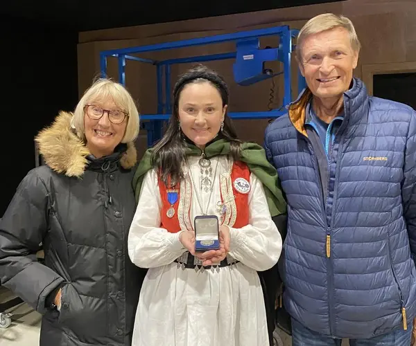 Foto av ekteparet Ann-Mari Hammer og Arve Strømman som flankerer Anja C. Solvik med Mor Norge-medaljen.