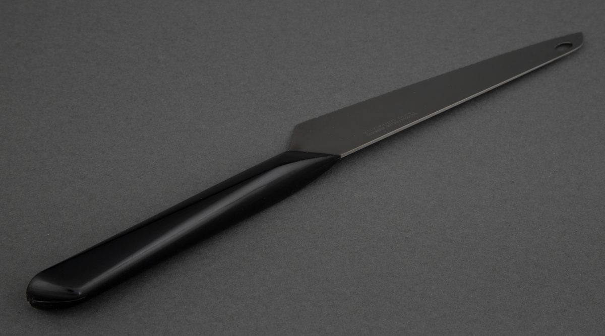 Brødkniv i rustfritt stål med svart, kantete nylonskaft. Skaftet er festet skrått til bladet. Utstanset oval øverst i knivbladet for oppheng.