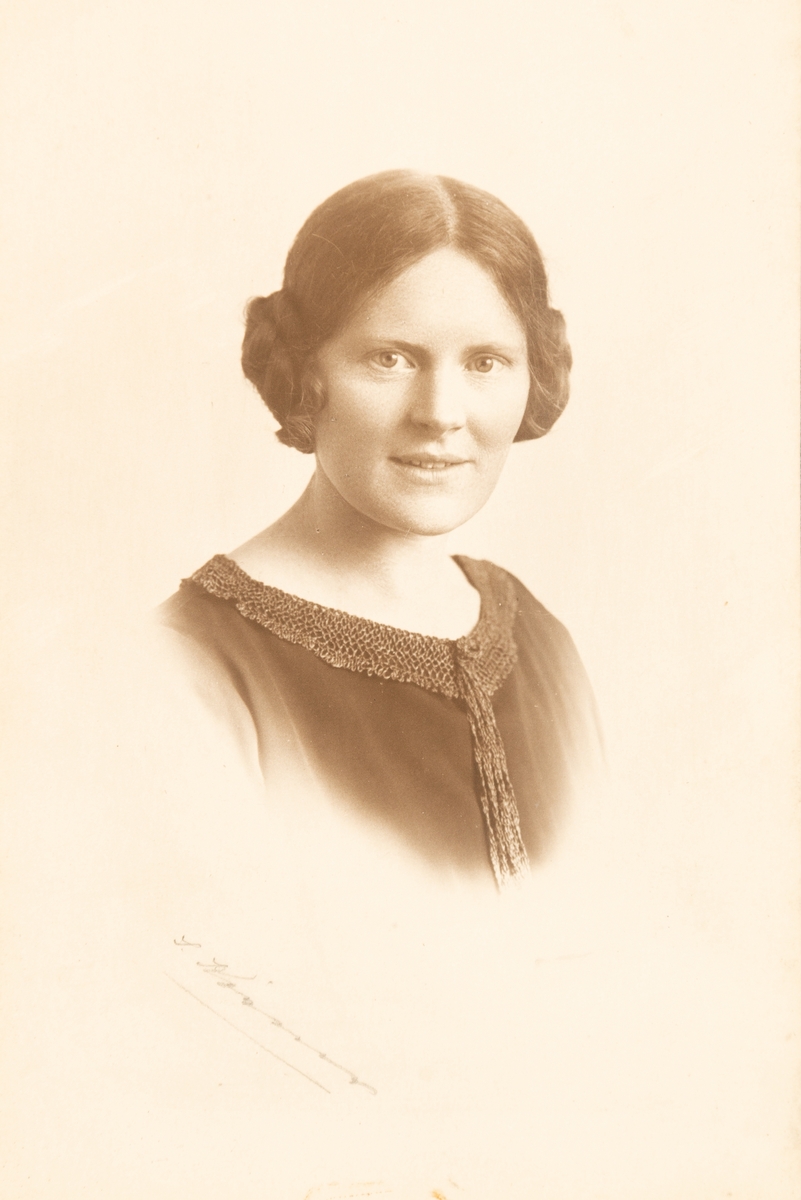Portrettfotografi av Anna Grostøl (1894-1962). Fotografiet er innrammet.