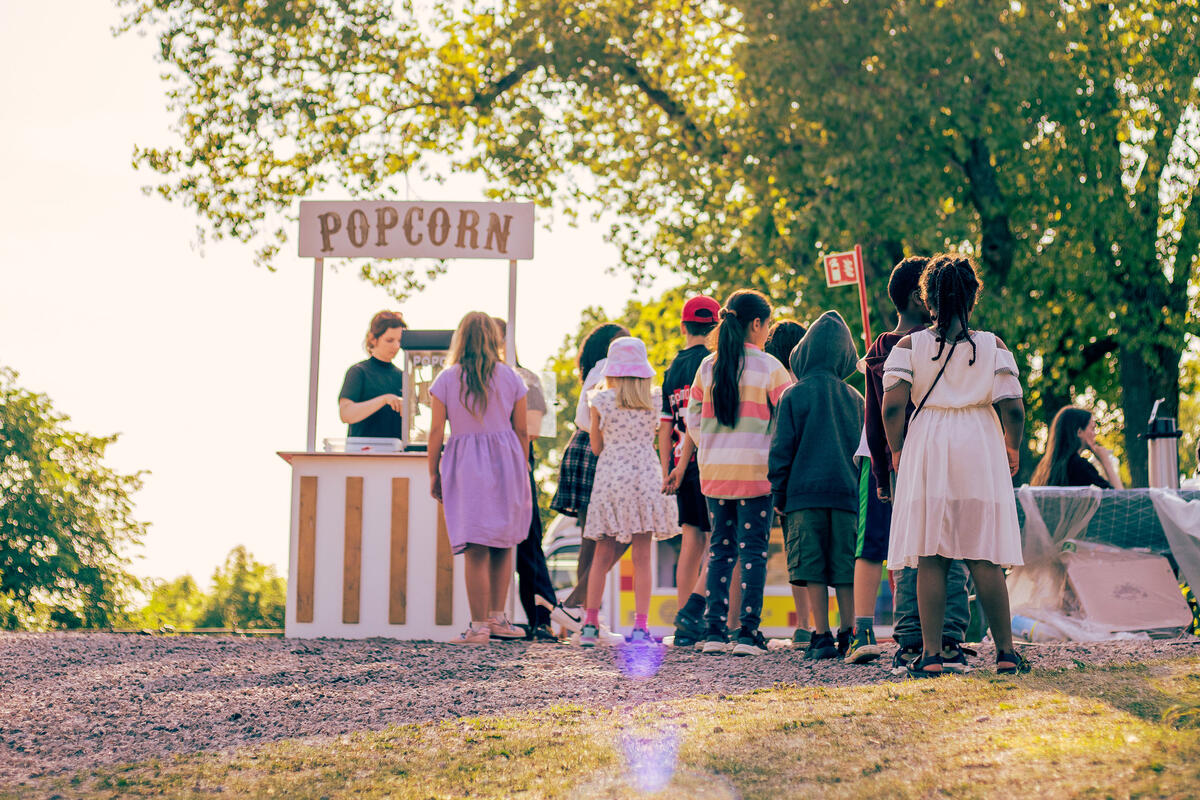 Barn som står i popcorn-kø i sommersol