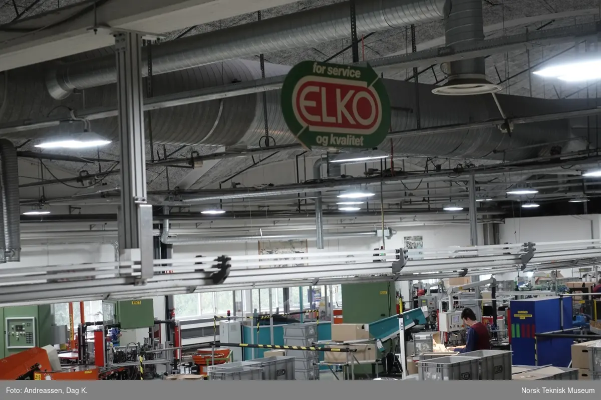Reklameskilt med ELKO-slagord som hang i taket i fabrikken mellom pakkeavdelingen og montasjehallen