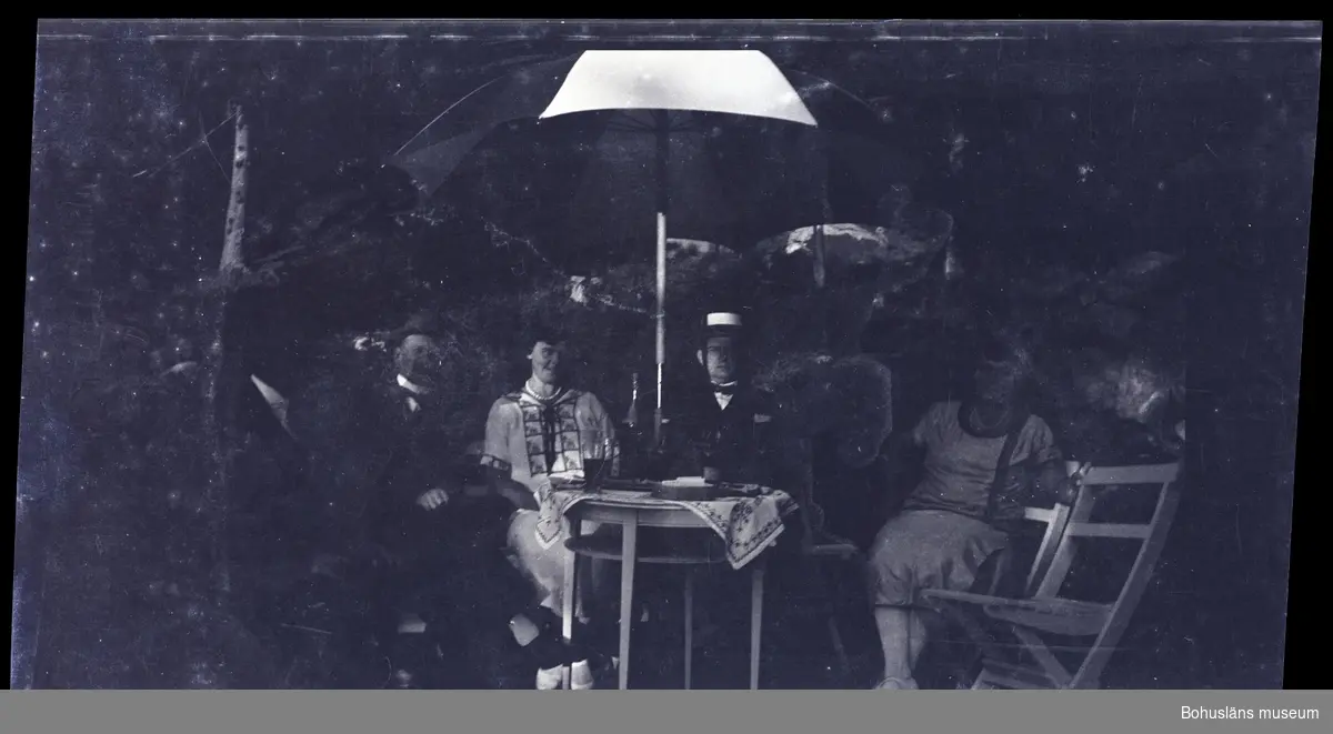 Fyra personer samlade vid ett bord under ett parasoll.