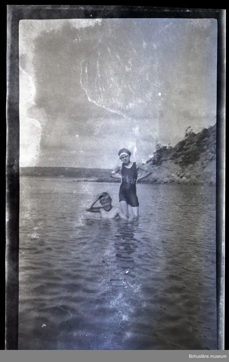 Två barn badar i havet.