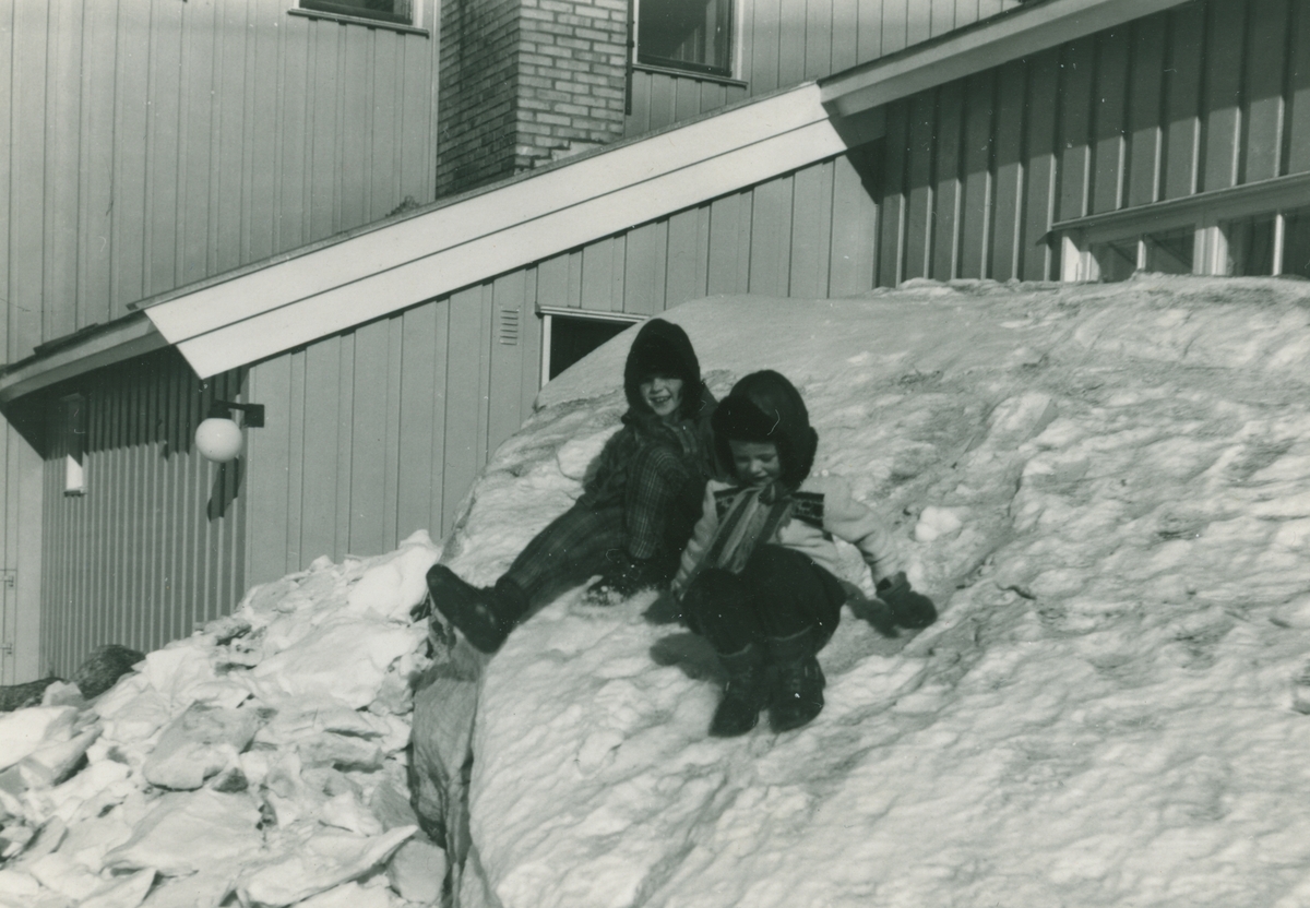 Tone Nødtvedt og Bodil Pettersen leker i snøen bak kirken vinteren 1960.