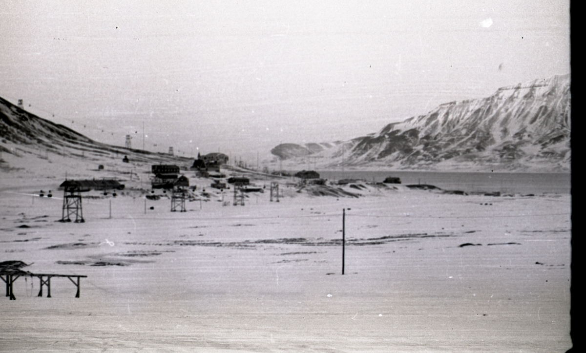 Oversiktsbilde over Gamle Longyearbyen og Skjæringa i mars 1958. Man kan se fjøset, bakeriet, Gamle Sykehus, kirken, sysselmannsgården og Rødhuset på Skjæringa.