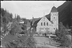 Rjukan kirke med park og grusplass foran kirken. Portal i tr