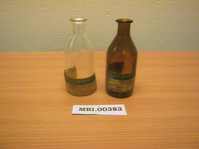 To sylindriske medisinflasker fra Moss Glasværk - en i klart og en i brunt glass.
