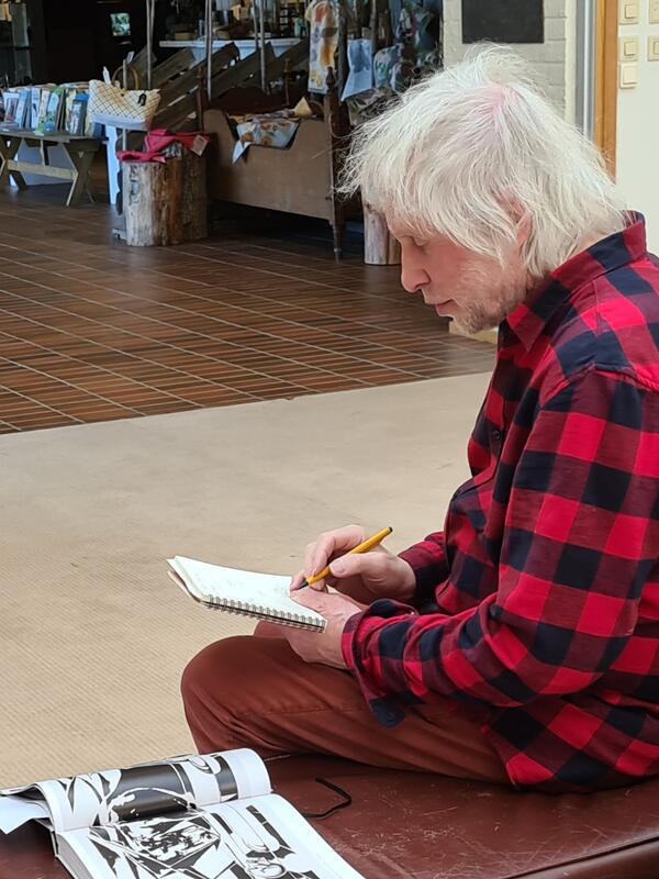 Bjørn Ransve sitter og noterer i en notatbok på Norsk skogmuseum.