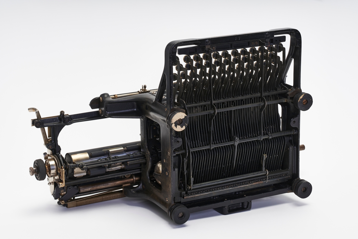 Manuell skrivemaskin med bred valse. Fargebånd med rød og sort farge sitter i.