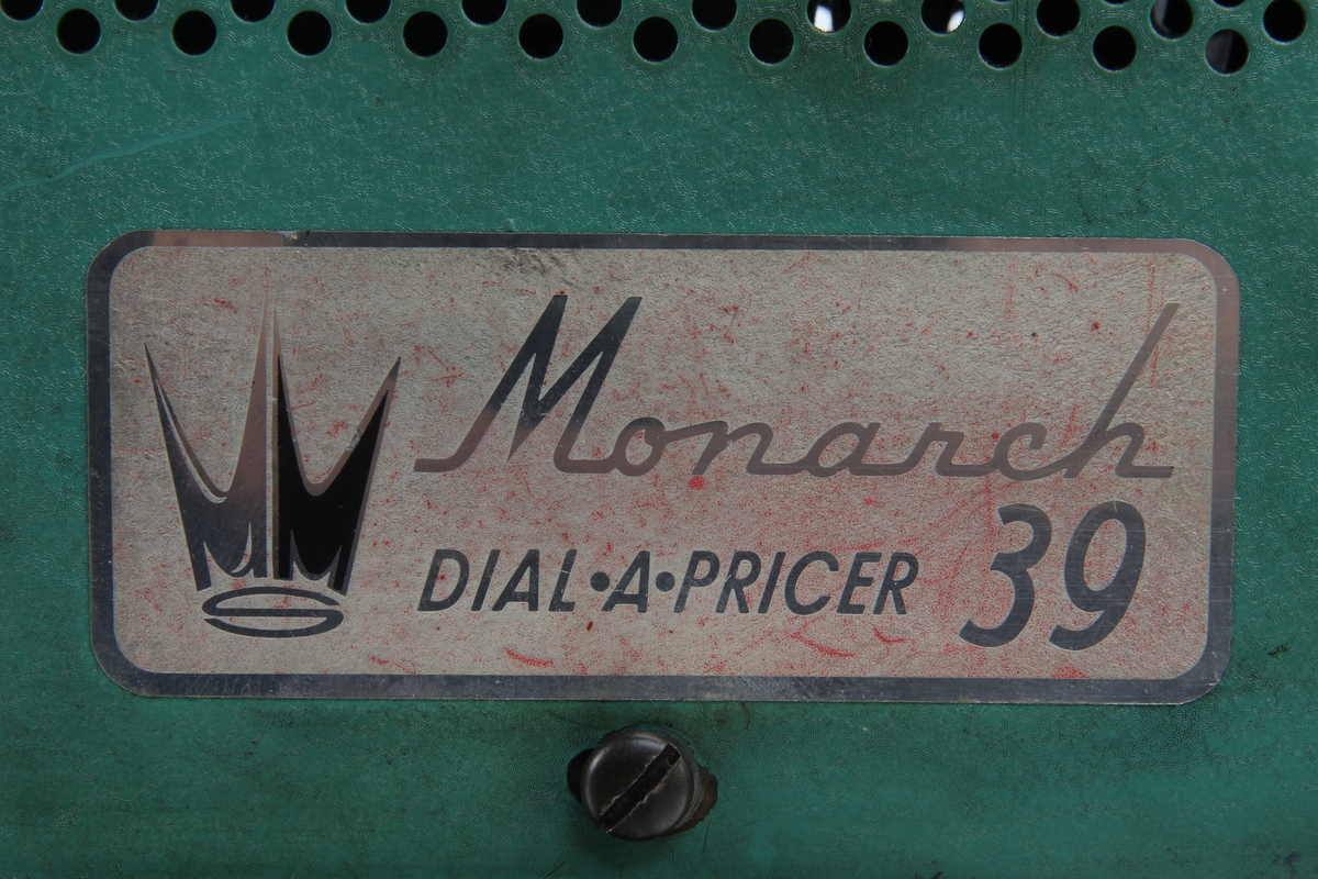 Prismerking apparat til bruk i butikk av typen "Monarch Dial a pricer 39". Apparatet er lakkert i en grønn "krympelakk".