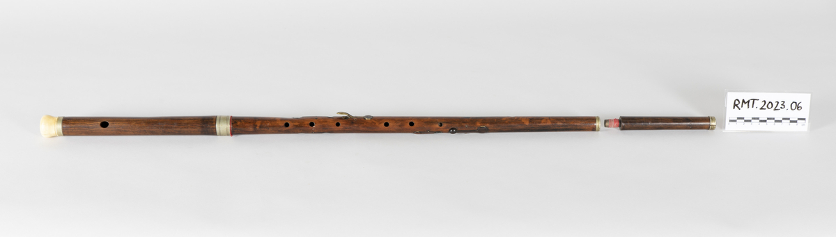 Fløyte i tre med elleve tonehull, hvorav fem med klaffer. Fløyten er lang, omtrent 85 centimeter, slik at den også kan brukes som spaserstokk.