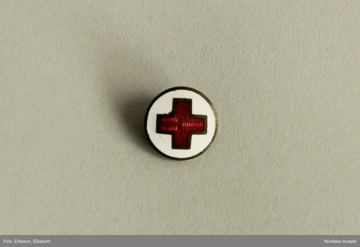 BROSCH, mässing, med rött kors i emalj inlagt på vit emaljbotten, för tjänstgörande vid Röda Korset. 

/Ulla-Karin Warberg 2023-06-15