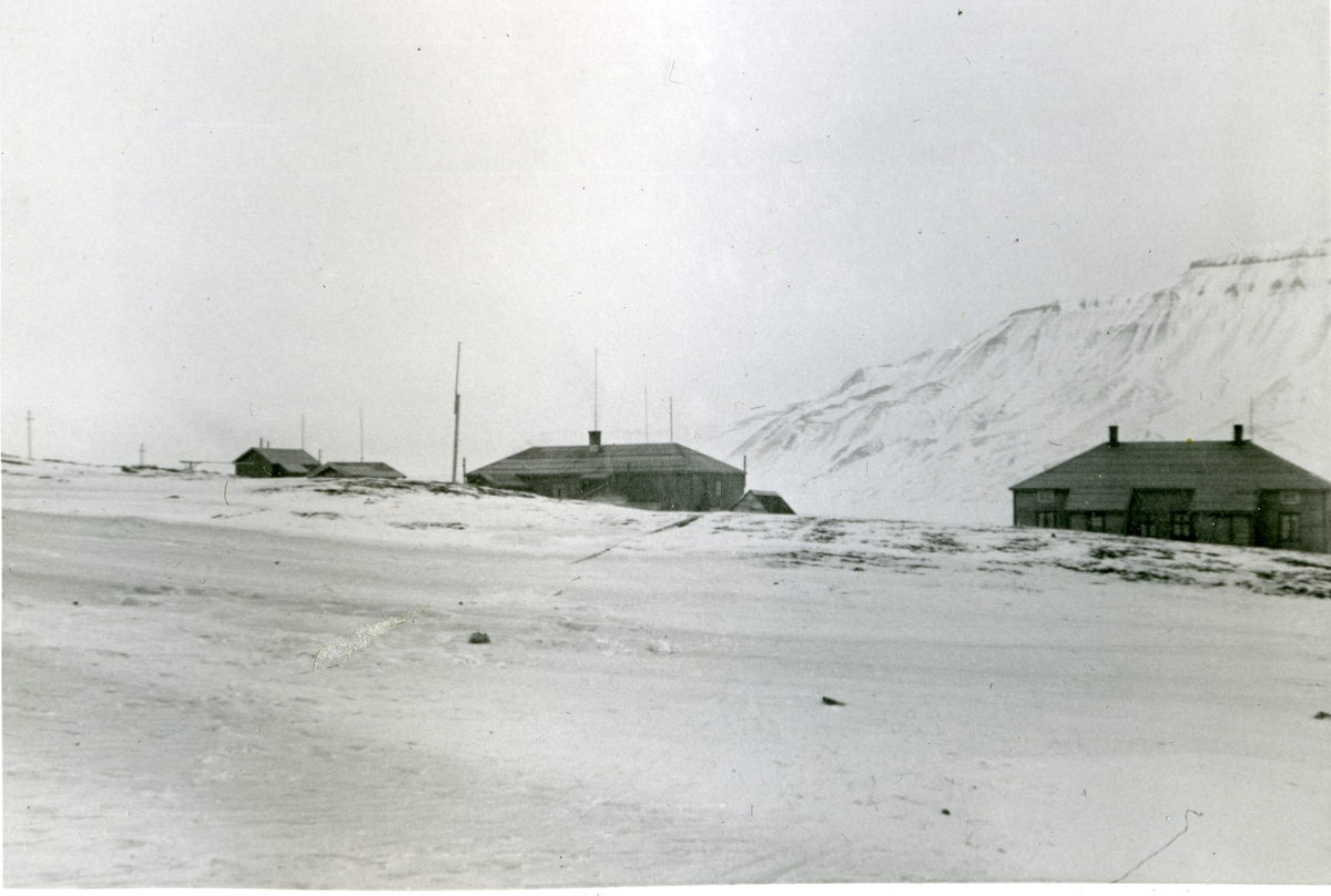 Til venstre Sysselmannsgården på Skjæringa i Longyearbyen i 1940/41. Til høyre ligger Bergmesterboligen. Begge byggene ble brent av tyske soldater 8.september 1943. Det lille huset helt til venstre, arresten, står fortsatt. Bilde fra albumet til Jens A. Bay, som bodde i Longyearbyen vinteren 1940/41.