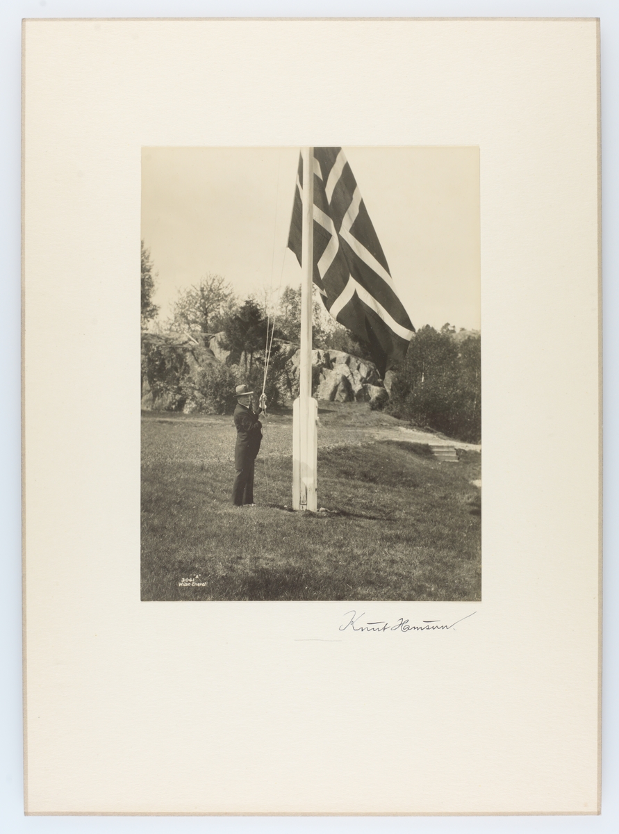 Portrett av Knut Hamsun som heiser det norske flagget. Hamsun har signert bildet.