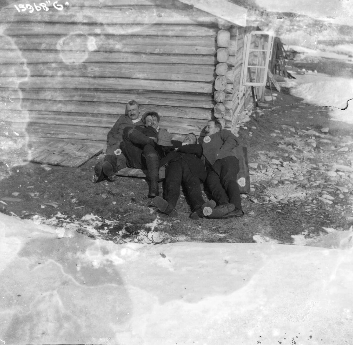 Fire menn slapper av utenfor en laftet tømmerhytte.