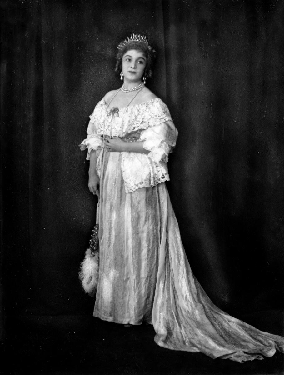 Portrett av skuespilleren og sceneinstruktøren Gerda Ring. Hun poserer i en ballkjole. med en tiara på hodet og med diverse perlesmykker.