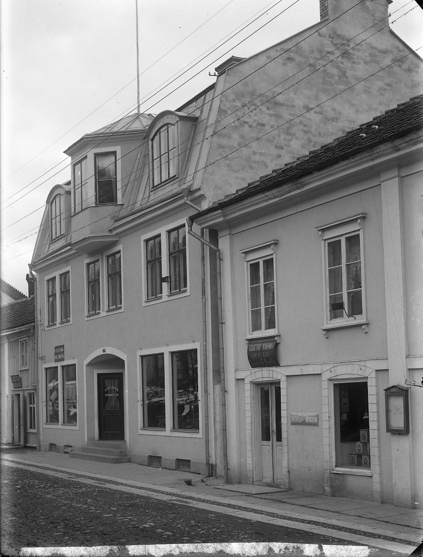 Fastigheter utmed Brahegatan i Gränna med O. Hellströms Garn- och trikåaffär samt Gustaf Rahms Speceri & diversehandel.