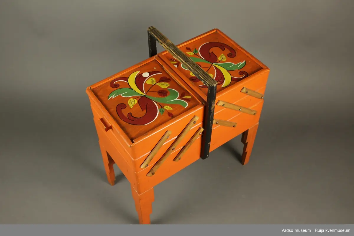 Jfr. Tilvekstprotokoll 1978-1984: Oransjemalt sybord med dekorerte ("rosemalte") lokk. To doble skuffeetasjer og hel skuff nederst. Har manglet ett ben, komplett pr 2022.