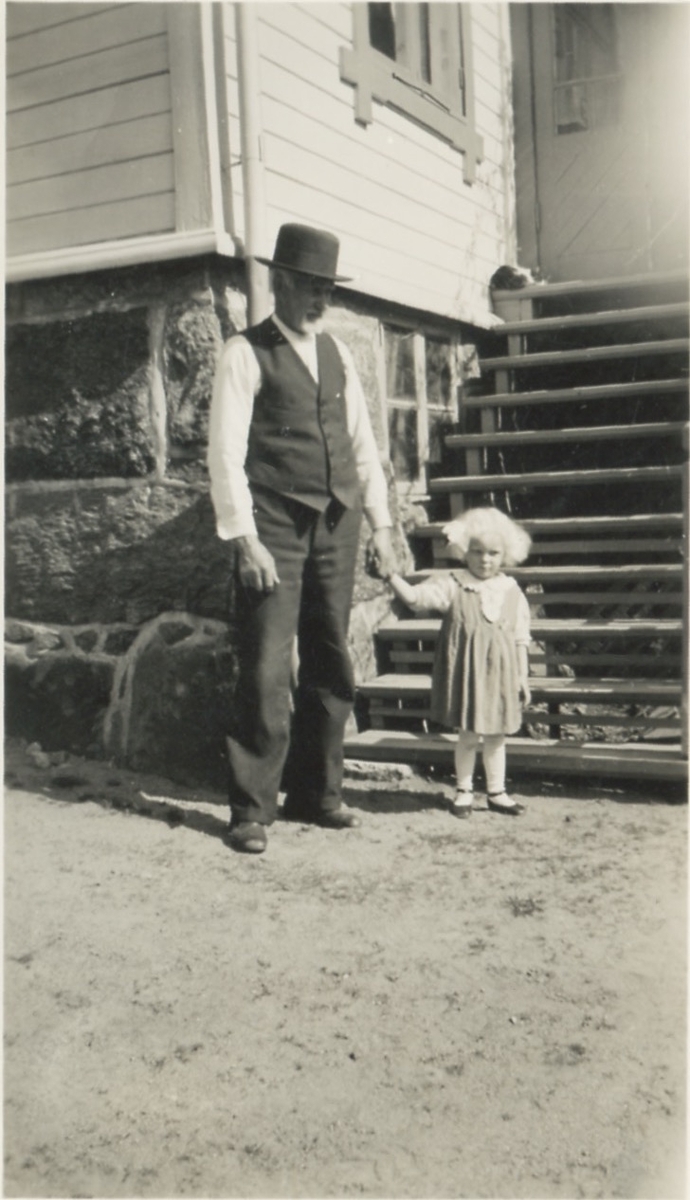 Johan Gustafsson (1867 - 1956) står på gårdsplanen tillsammans med sitt barnbarn, Kållered Stom "Nygård" 1940-tal.