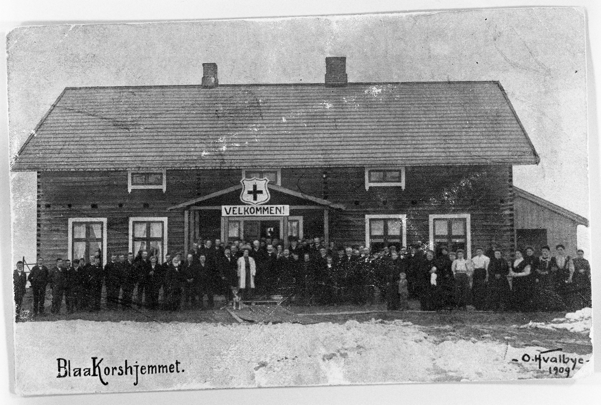 Blåkorshjemmet på Eina, Vstre Toten, ca. 1909. Postkort som viser hovedbygningen med en rekke personer foran.