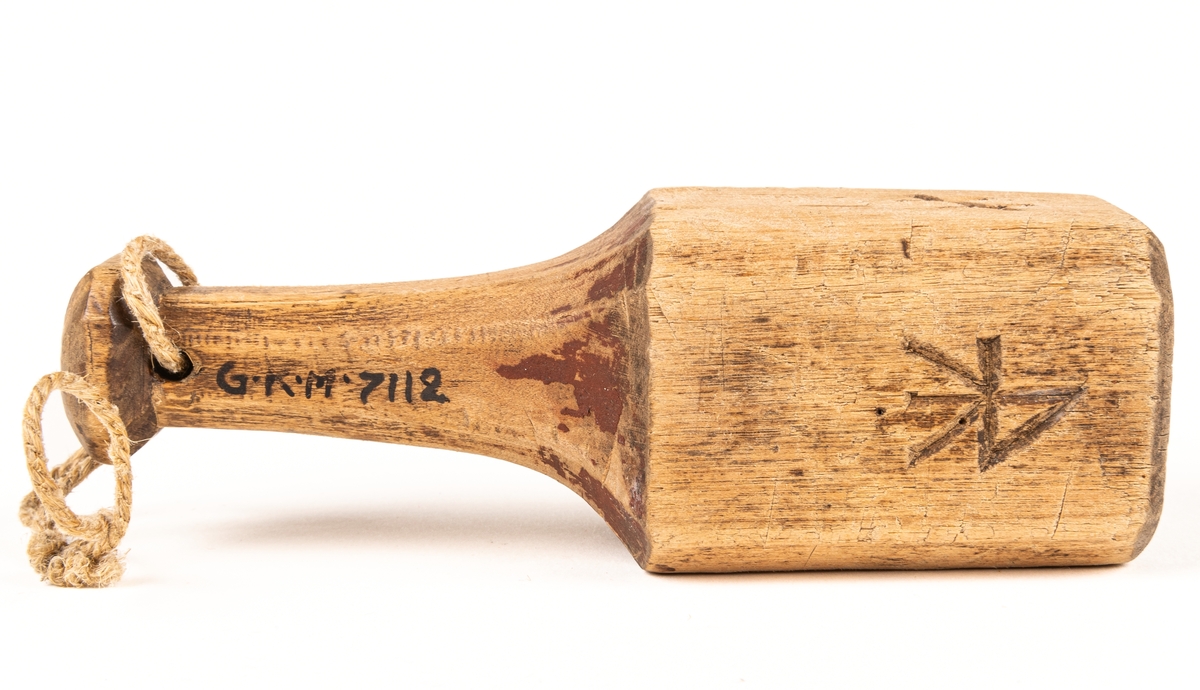 Plogklubba av trä, fyrsidig med handtag och inristade bomärken. Daterad 1829.